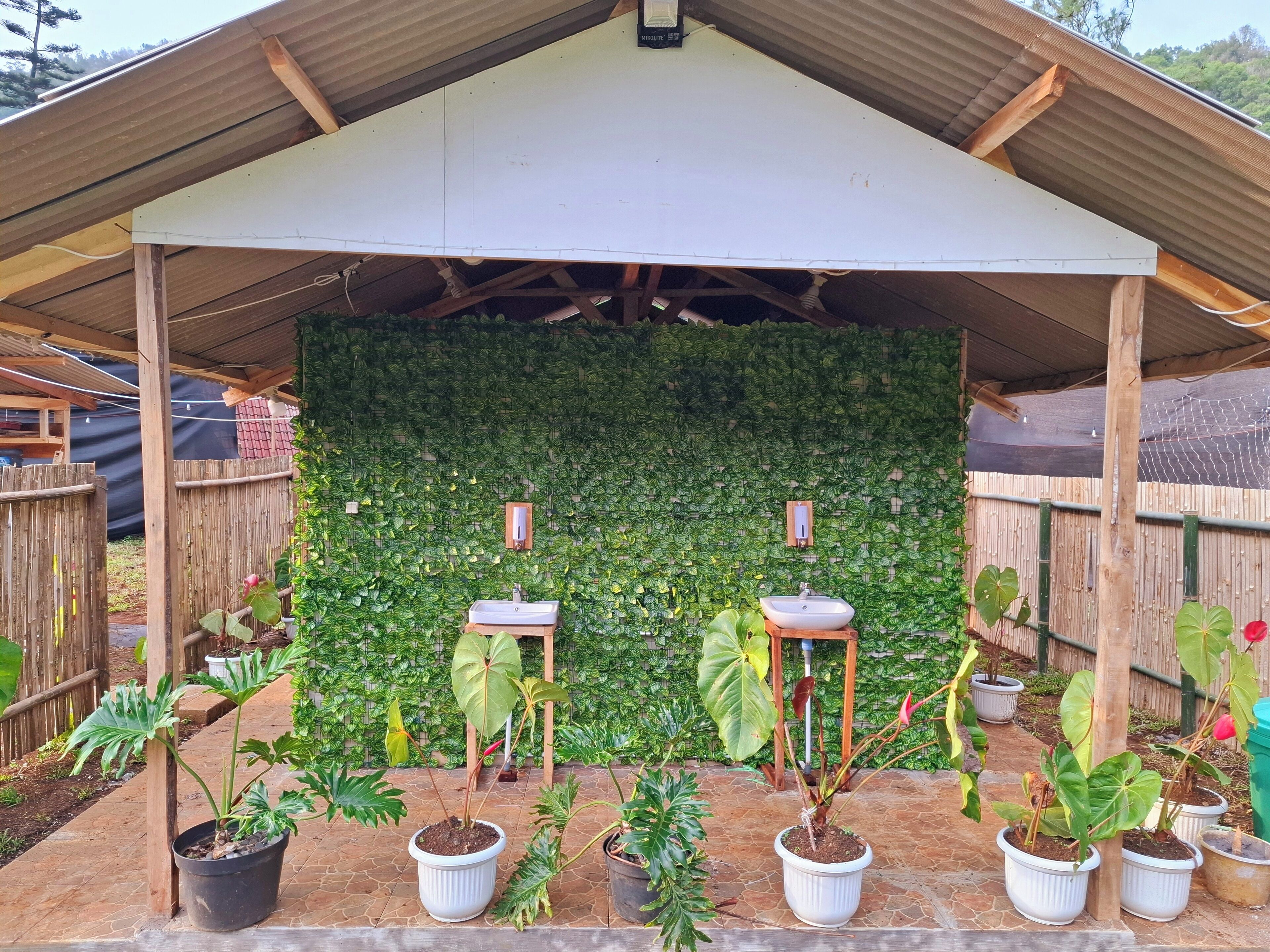 A covered patio area with two white sinks and a wooden bench.