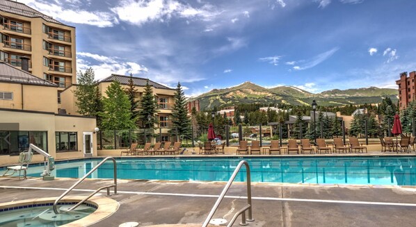 Un espace piscine avec des chaises longues et une vue sur les montagnes.