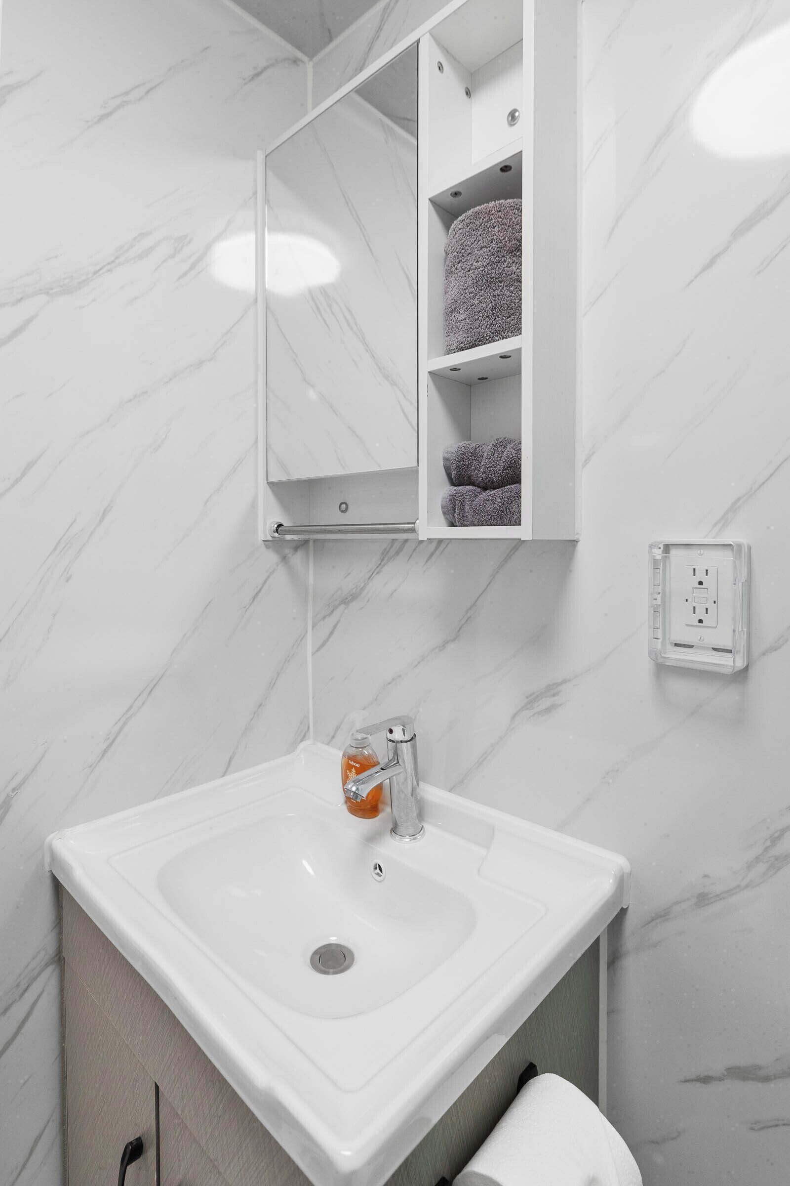 A bathroom with a white sink, a mirror, and a towel rack.