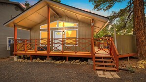 A cabin with a covered porch, a wooden deck, and a small staircase leading to the entrance.