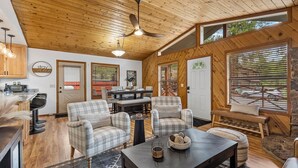A cozy cabin interior with a dining area, seating, and a kitchen.