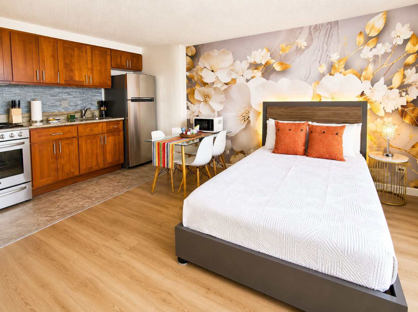 Habitación de hotel moderna con cocina, zona de comedor y una cama grande con cabecero.