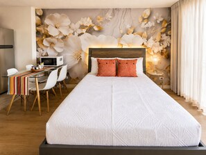 A hotel room with a bed, a desk with a computer, and a wall with floral artwork. - Free Parking Newly Renovated 12th FL Great View (Honolulu)