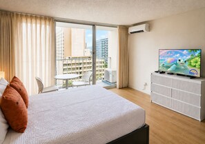 A hotel room with a bed, a TV, a balcony with a view of buildings, and an air conditioning unit. - Free Parking Newly Renovated 12th FL Great View (Honolulu)
