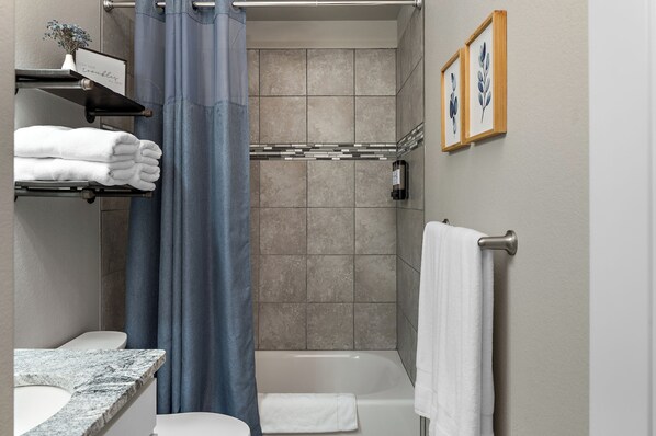 A bathroom with a shower, a toilet, a sink, and a towel rack.
