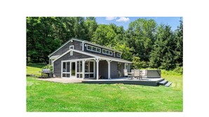 Une maison à deux étages avec un porche couvert et une petite terrasse.
