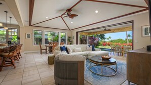 A spacious living area with a large sectional sofa, a round coffee table, and a ceiling fan.