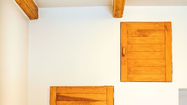 A bathroom with wooden cabinets and white tiled walls.
