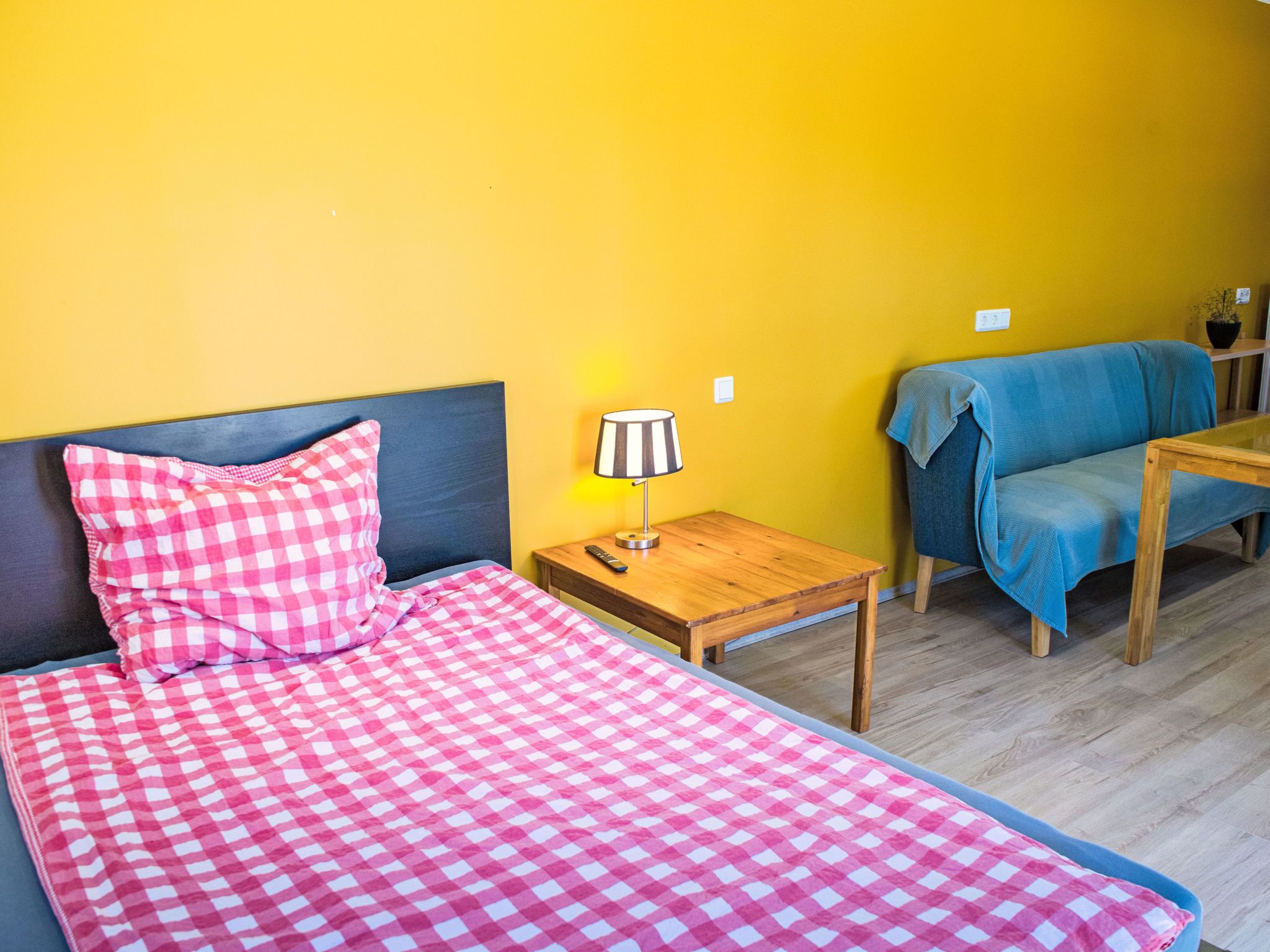 Ein Zimmer mit einem Bett, einem kleinen Tisch mit Lampe und einem Sofa.
