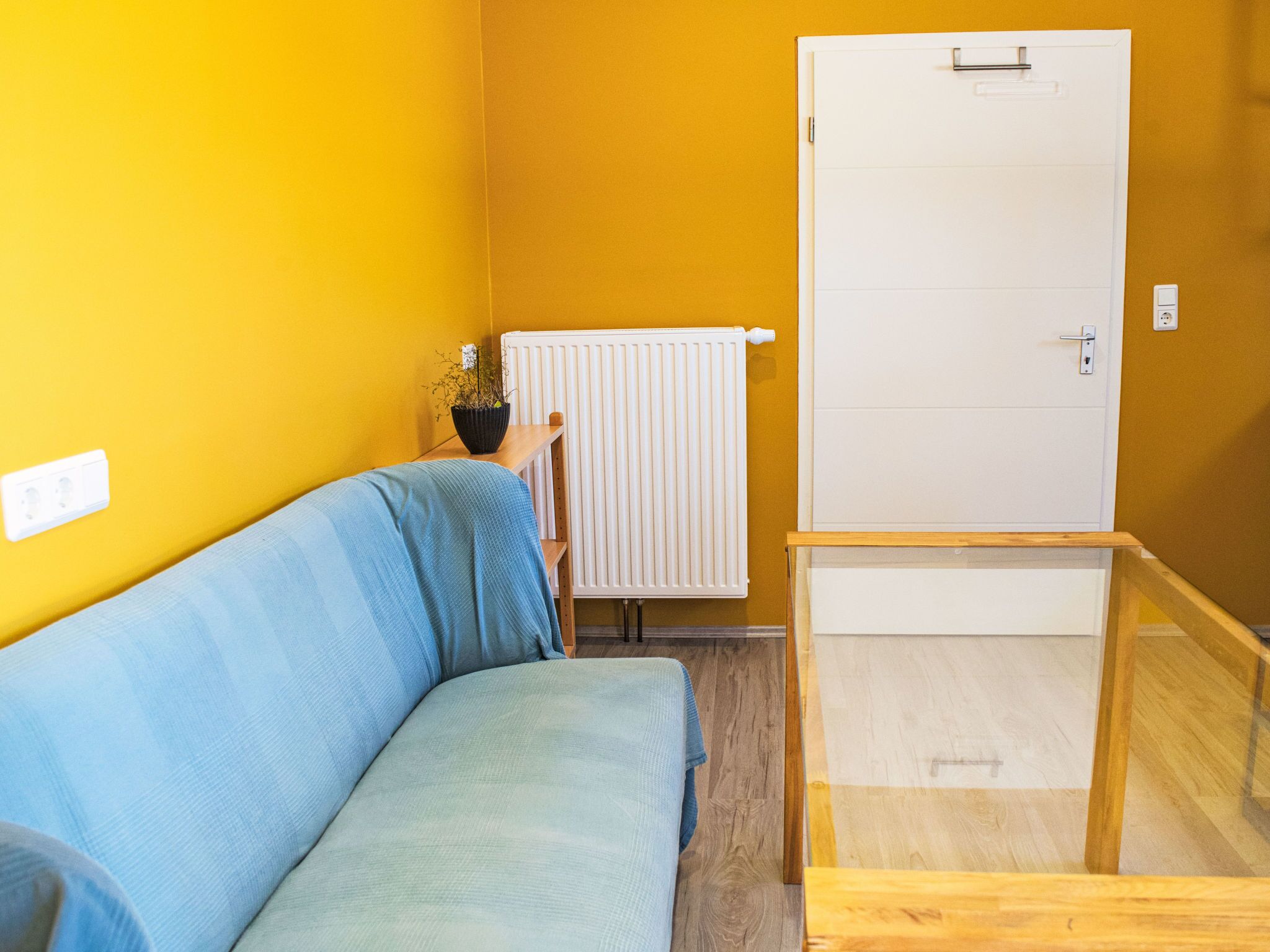 Ein Zimmer mit einem blauen Sofa, einem weißen Heizkörper und einer weißen Tür.