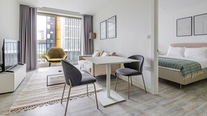Ein modernes Hotelzimmer mit einer Couch, einem Esstisch, einem Fernseher und einem Bett.