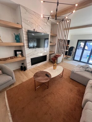 Uma sala de estar moderna com televisão de tela plana, lareira, mesa de centro redonda e sofá.