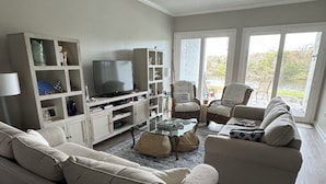 Ein Wohnzimmer mit einer Couch, Sesseln, einem Fernseher und einem Bücherregal.