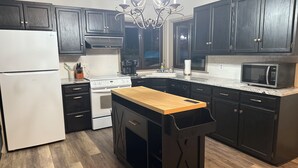 Una cocina moderna con armarios oscuros, un refrigerador blanco, una isla de madera y una araña.