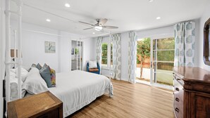 A bedroom with a bed, a wooden nightstand, a ceiling fan, and a view of the outdoors through a sliding glass door. - Charming 3-bedroom house in lovely San Clemente with AC, Walk to the Pier! (San Clemente)