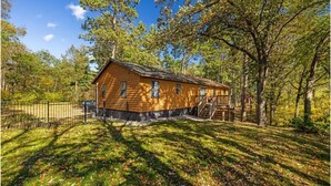 A wooden cabin with a porch, surrounded by trees and a fenced yard. - Spacious 5BR Cabin on 6th Crow Wing Lake Near Nevis, MN (Nevis)