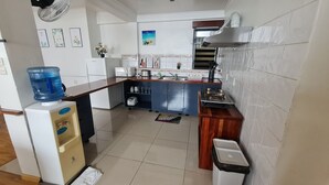 Una cucina compatta con frigorifero, dispenser d'acqua, fornello, lavello e pensili.
