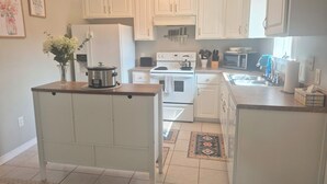 A kitchen with white cabinets, a stove, a microwave, and a sink.