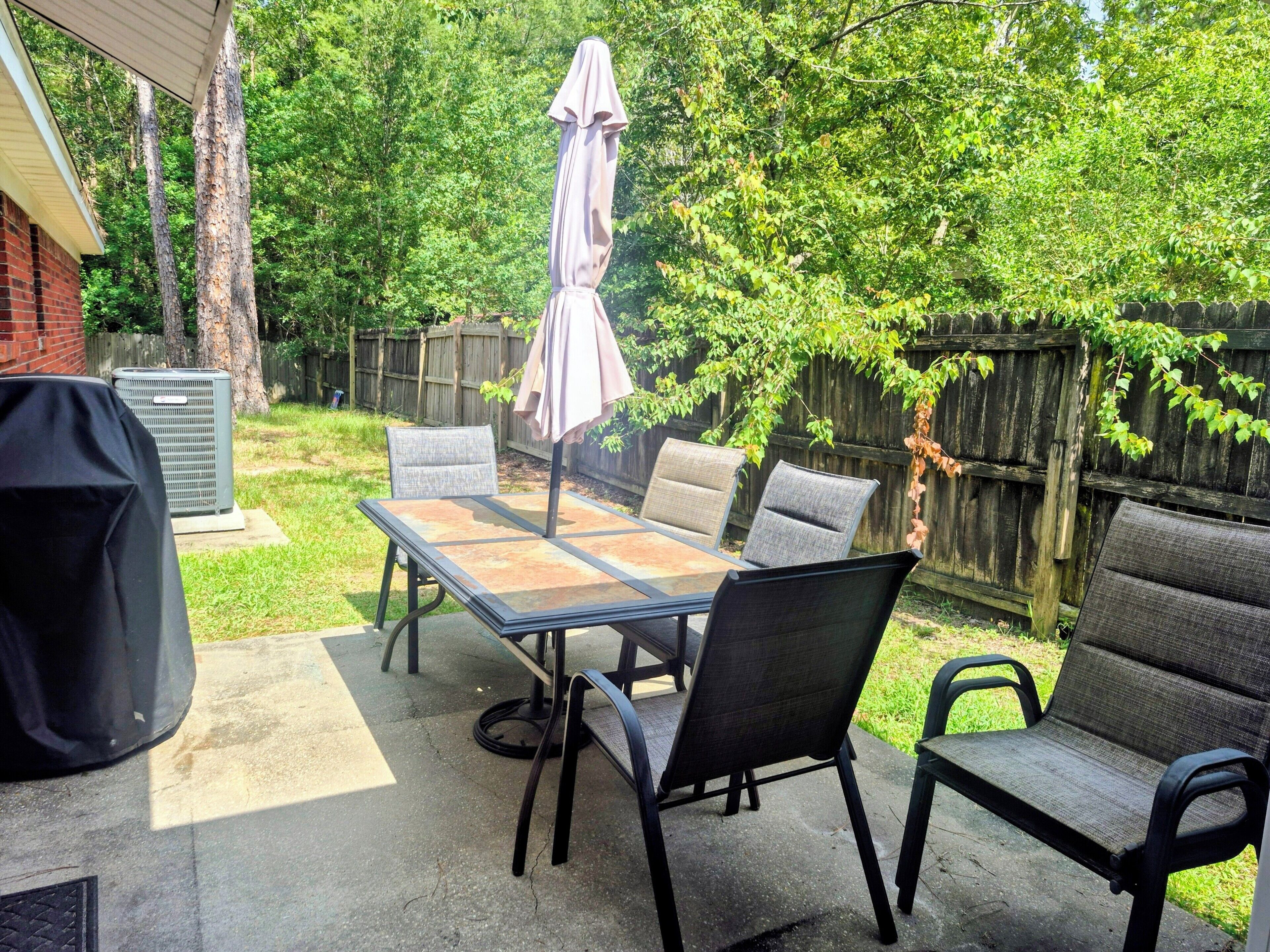 Eine Terrasse im Freien mit Tisch, Stühlen, Sonnenschirm und Grill.