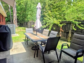 Une terrasse extérieure avec une table et des chaises, un parasol et un barbecue.