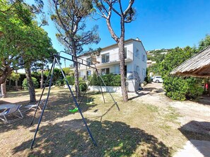 Um bairro residencial com um prédio branco, balanço e uma pequena cabana.