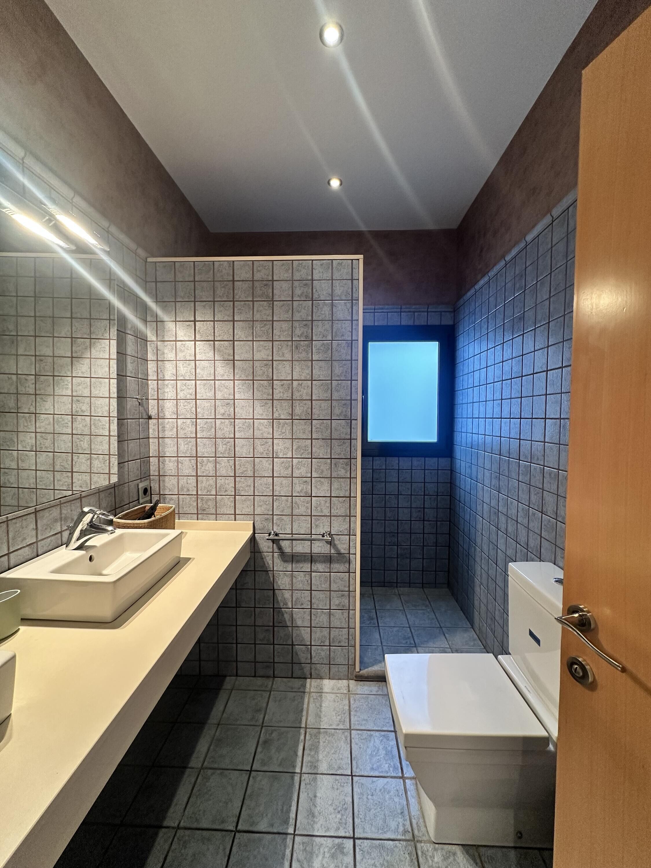Een moderne badkamer met een grote spiegel, een wastafel, toilet en een douchehoek.