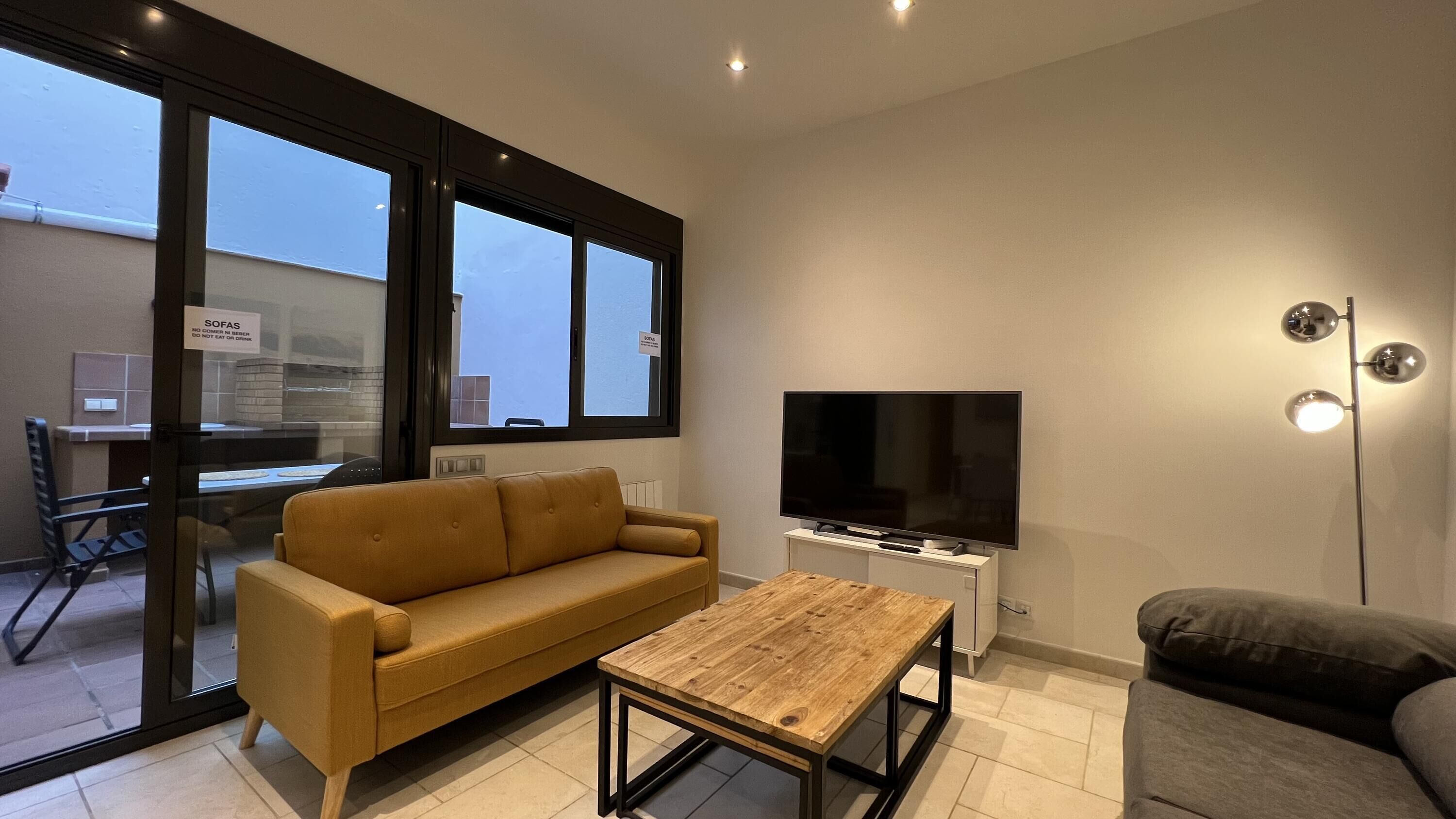 A modern living room with a sofa, a coffee table, a TV, and a floor lamp.