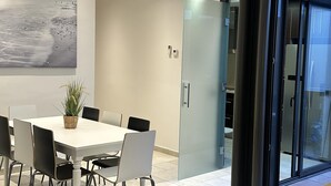 Ein modernes Wohnzimmer mit grauem Sofa, einem Esstisch mit Stühlen, einem großen abstrakten Gemälde und einer Glastür zum Balkon.