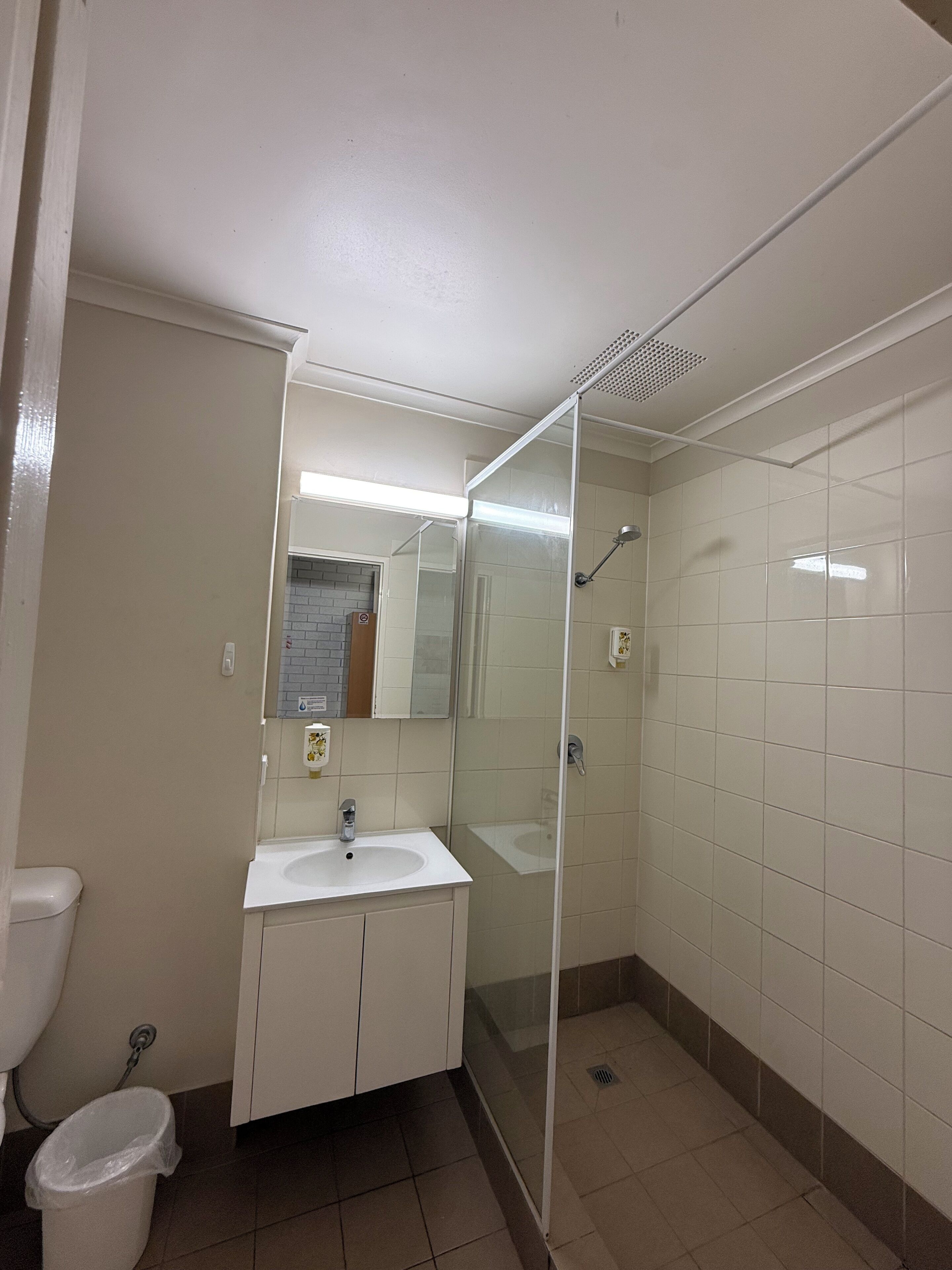 Un bagno con lavandino bianco, specchio e cabina doccia.