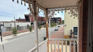 A covered porch with a white railing, a brick wall, and a view of a street with cars and buildings. - Budget Motel Midland (Midland)