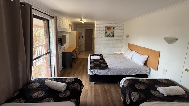 A hotel room with two beds, a desk, a chair, a television, and a bathroom visible through an open door. - Budget Motel Midland (Midland)