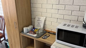 A kitchenette with a microwave, a sign prohibiting smoking, and a tray with coffee cups and snacks. - Budget Motel Midland (Midland)