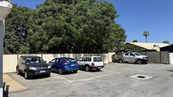 A parking lot with several cars, including a black SUV, a blue car, and a white SUV.