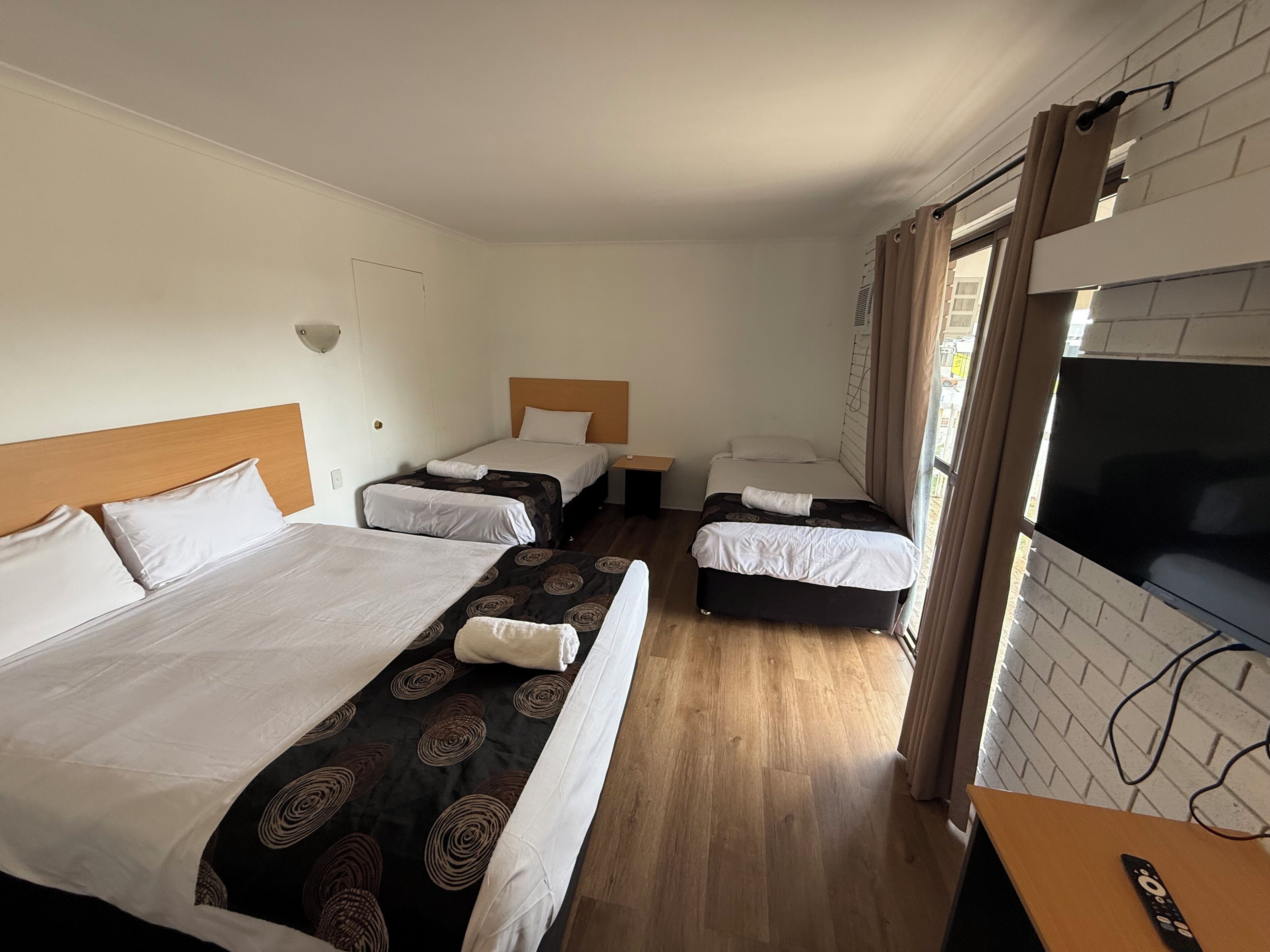 Une chambre d’hôtel avec deux lits, une télévision et un plancher en bois.