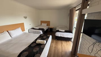 Habitación de hotel con dos camas, un televisor y piso de madera.