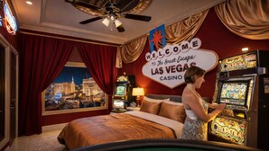 Habitación de hotel con vistas a la ciudad, una cama, una máquina tragamonedas y un letrero que dice "Welcome to The Great Escape LAS VEGAS CASINO".