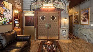 Entrada de teatro con un cartel que dice 'Gran Teatro Jumanji Escapade', un sofá de cuero elegante, un tablero de ajedrez y una mesa de centro de estilo vintage.