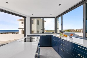 A modern kitchen with a large window, a view of the sea, and a balcony. - Villa Panorama by Ezoria Villas (Kouklia)