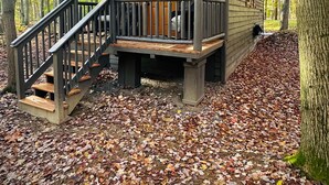 A cabin with a wooden deck and a staircase leading to a porch. - Hidden Oaks | Lodge Cabin | Unit 3 (Birch Run Township)