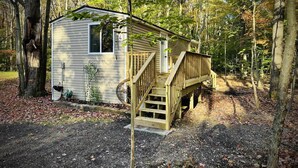 A small cabin with a wooden deck and a single staircase leading to the entrance.
