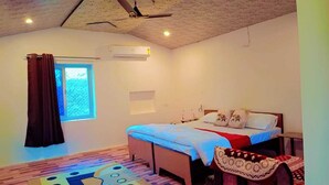 Une chambre à coucher comprenant un lit, un ventilateur de plafond, un climatiseur, une fenêtre avec des rideaux et un tapis à motifs.