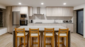 A modern kitchen with a central island, wooden chairs, and built-in appliances. - Casa do Tojal - A refuge in the Minho mountains (Igreja)