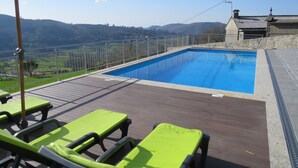 A swimming pool with a wooden deck, green lounge chairs, and a view of the countryside. - Casa do Tojal - A refuge in the Minho mountains (Igreja)
