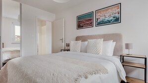 Une chambre moderne avec un grand lit, deux tables de chevet et une tête de lit.