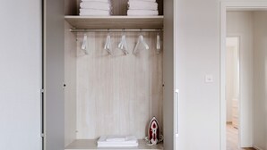 Un dressing avec espace pour suspendre les vêtements et des étagères, un fer à repasser et des serviettes soigneusement pliées.