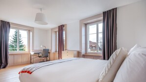 Une chambre d’hôtel moderne avec un grand lit, un bureau et une vue sur la ville.