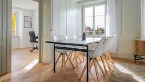 Une salle à manger moderne avec une grande table, des chaises blanches et une vue par la fenêtre.