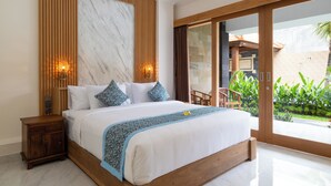 Un dormitorio moderno con una cama grande, cabecera de madera y vistas a un jardín a través de un ventanal corredero.