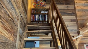 A wooden staircase with a bookshelf filled with books and a colorful ball collection. - Chalet Les Ravaires, Morgins (Morgins)