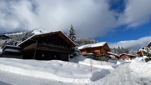 A snow-covered village with wooden buildings, a clear sky, and a mountain in the background. - Chalet Les Ravaires, Morgins (Morgins)